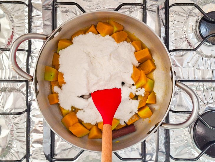 Açúcar sendo adicionado à abóbora cozida dentro da panela.