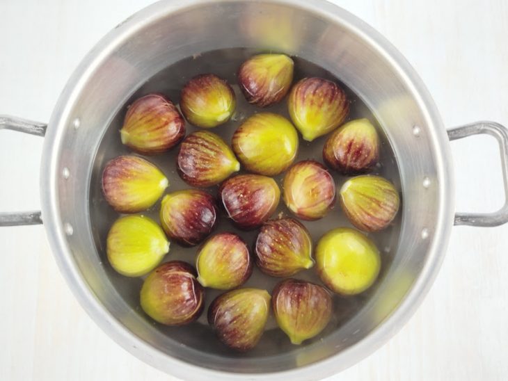 Figos sendo cozidos em panela grande com água quente.