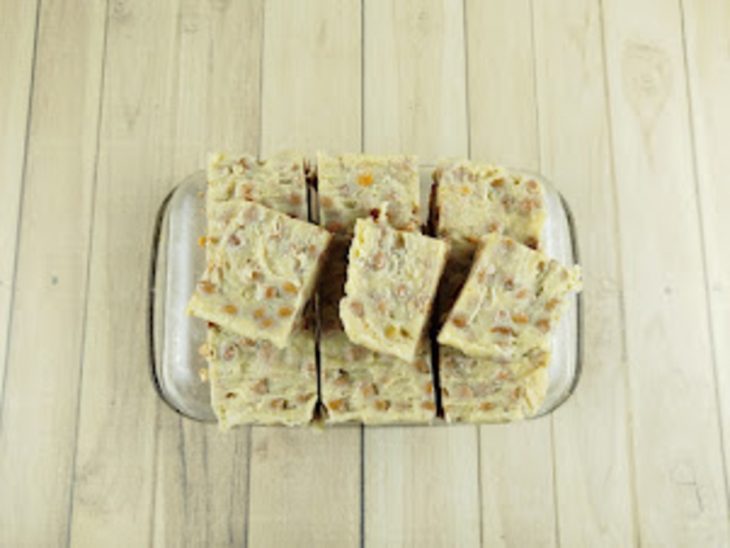 Doce espalhado e nivelado em forma forrada com papel-manteiga.