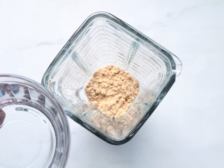 Água sendo adicionada aos poucos enquanto a mistura é batida até formar um creme homogêneo.