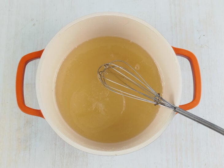 Gelatina hidratada sendo incorporada à calda quente e misturada até dissolver.