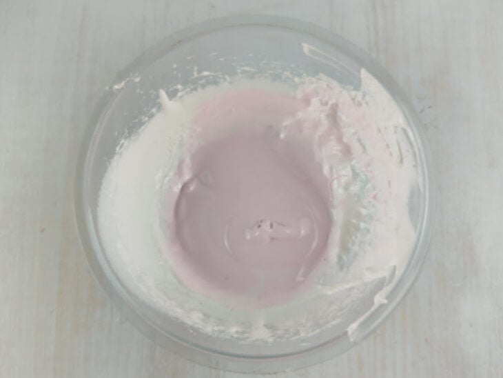 Essência de morango e corante rosa sendo misturados à metade restante do doce.