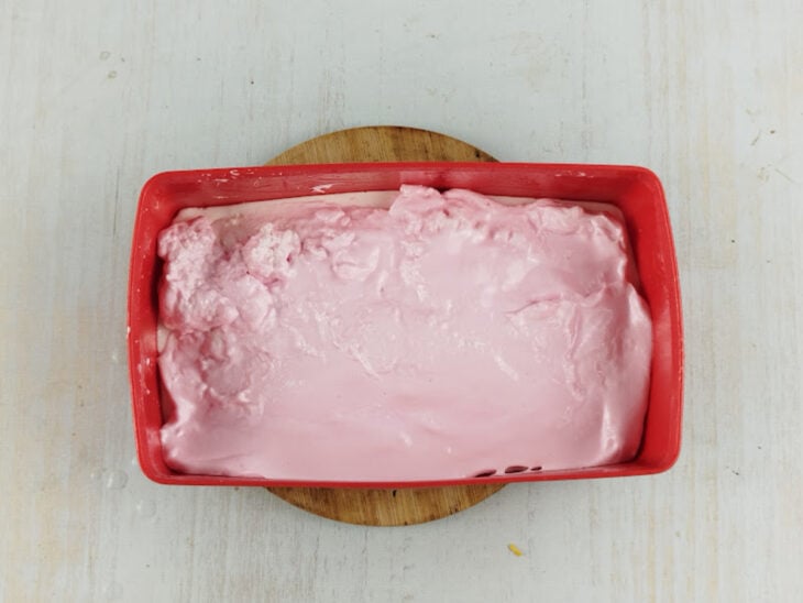 Camada rosa sendo distribuída sobre a camada branca e nivelada na forma.