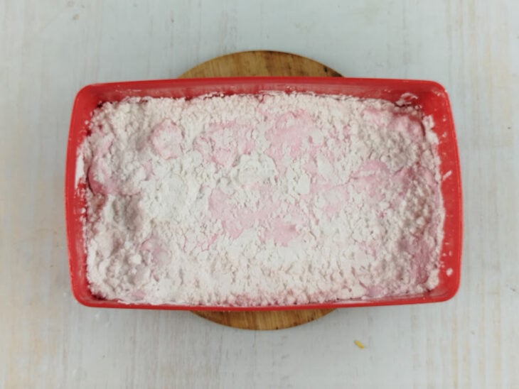Superfície do doce sendo polvilhada com açúcar impalpável após breve descanso.