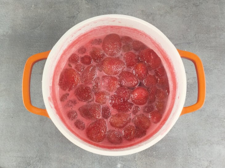 Doce fervendo na panela enquanto a espuma é retirada da superfície.