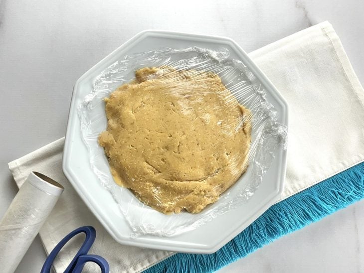 Um prato contendo um brigadeiro de amendoim coberto com plástico filme.