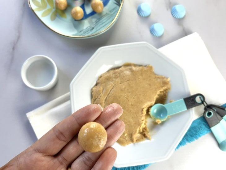 Bolinhas de doce de amendoim sendo boleadas.