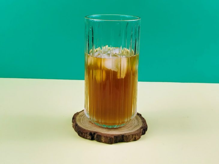 Gelo, chá, rum e suco de limão adicionados num copo.