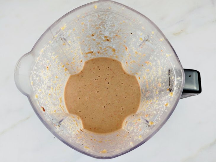 Um liquidificador com a mistura do camarão seco moído, castanha-de-caju, amendoim, caldo, gengibre e leite de coco.