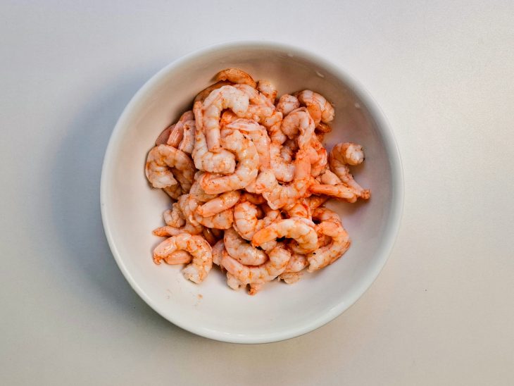 Numa tigela, camarões temperados com os camarões com sal, páprica defumada, pimenta-do-reino.