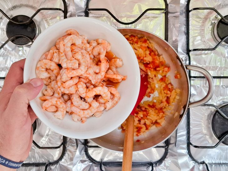 Na panela, camarão sendo incorporado.