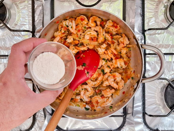 Na mesma panela, farinha, o cheiro-verde e a água sendo adicionados.