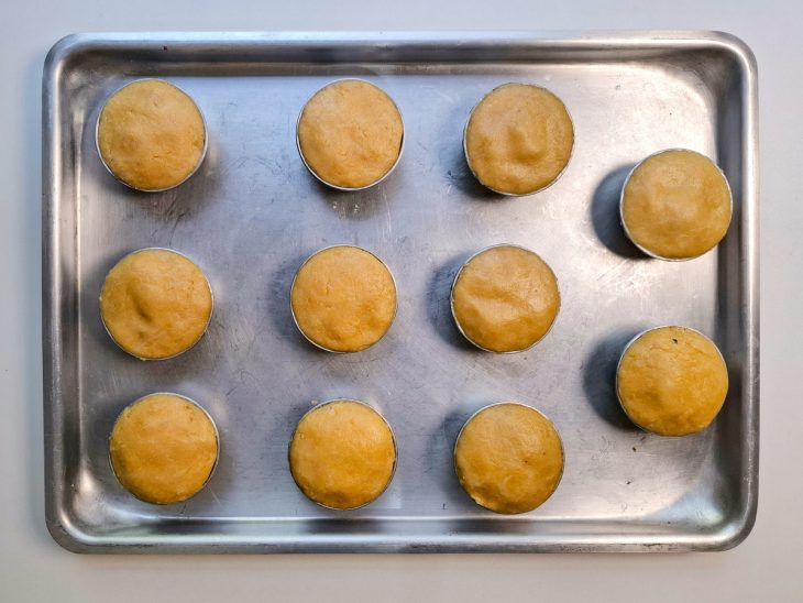 Numa assadeira, as forminhas com todas as empadas já fechadas.