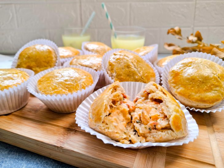 Empadas prontas, uma cortada ao meio mostrando o recheio.