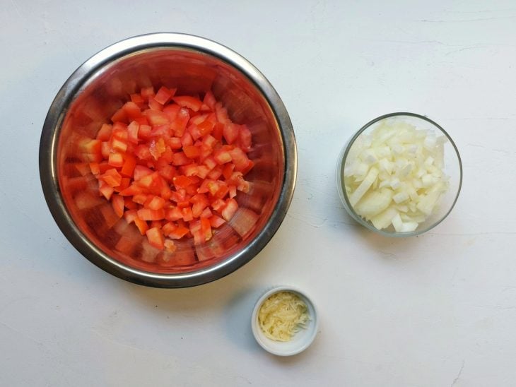 Recipientes distintos com ingredientes diferentes (tomate, alho e cebola)