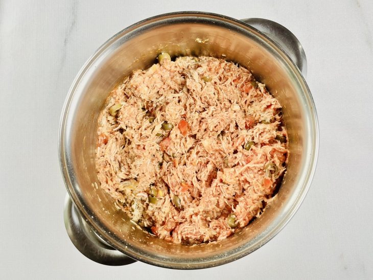 Recheio de frango sendo misturado com molho de tomate e requeijão.