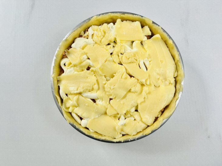 Recheio de frango já frio sendo espalhado sobre a massa.