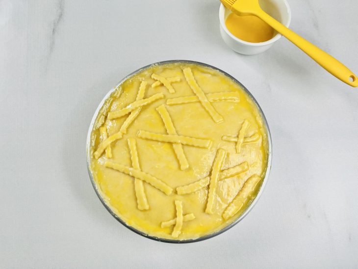 Gema sendo pincelada sobre o topo do empadão cru.