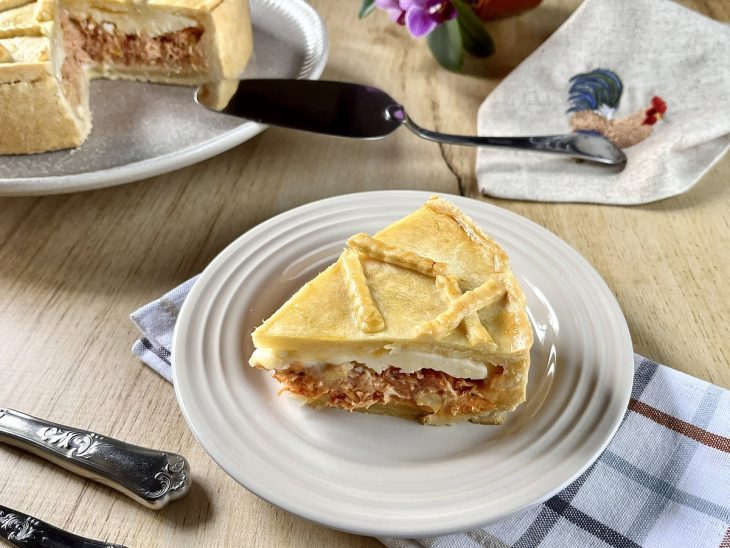 Fatia do empadão servida em prato, mostrando recheio cremoso.