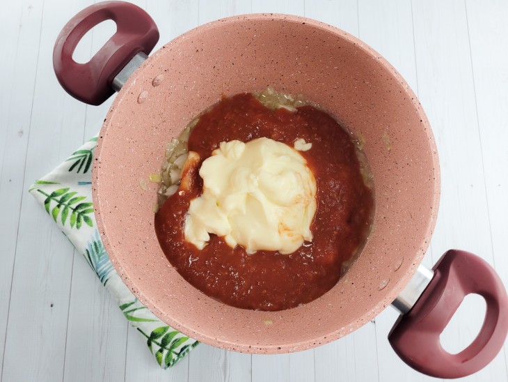 Molho de tomate e requeijão colocados na panela.