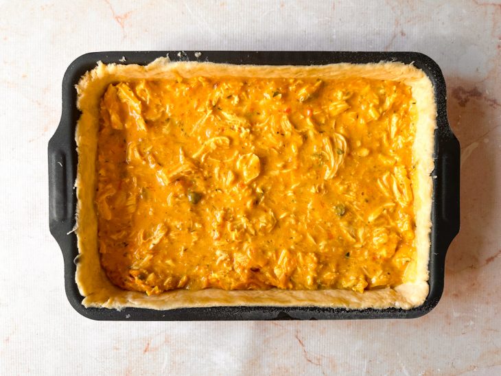 Recheio de frango espalhado de maneira uniforme sobre a massa.