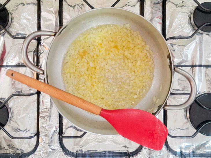 Cebola refogada no azeite numa panela.