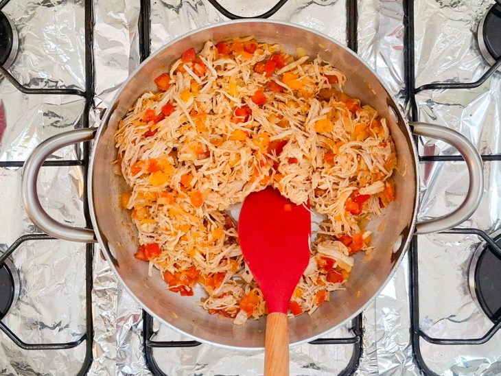 Pimentão, tomate e frango adicionados na panela.