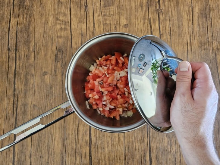 Panela com tomates e temperos sendo fechada.