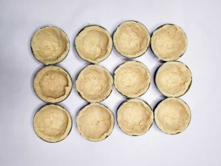 Porções da massa dispostas em forminhas de empadinha.