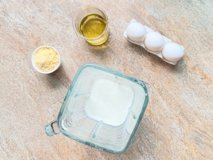 Ovos, leite, queijo ralado e óleo separados.