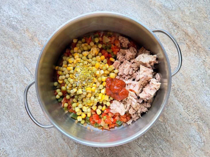 Atum, milho, ervilha e extrato de tomate adicionados na panela.