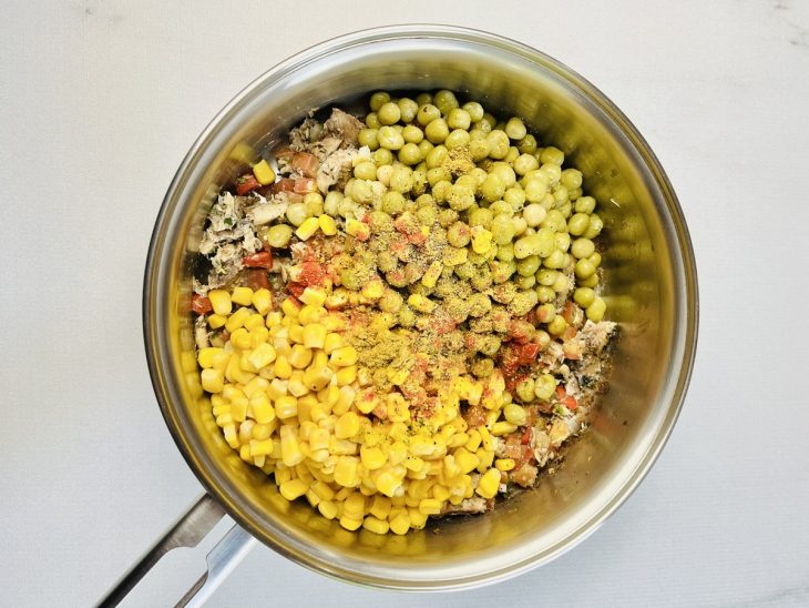 Milho, ervilha e temperos adicionados na panela com sardinha refogada.