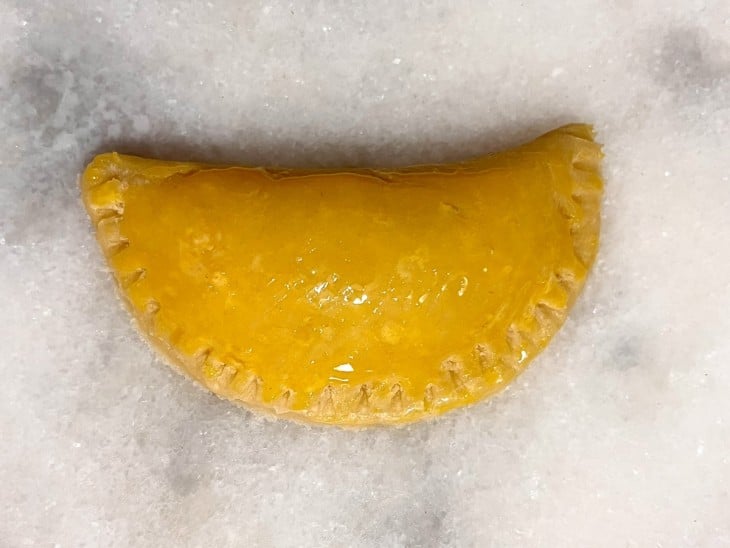 Uma empanada crua e pincelada com gema.