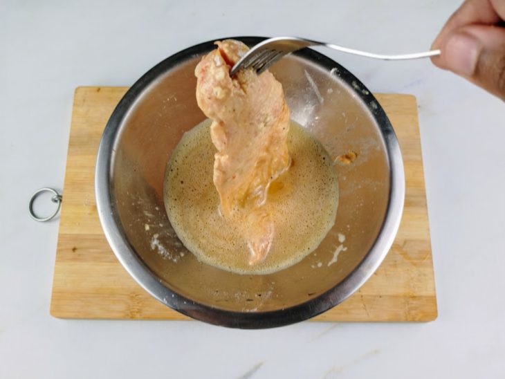 Filé de frango mergulhado na mistura de ovos temperados.