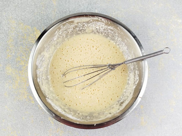 Massa recebendo leite, farinha peneirada e coco ralado com textura leve.