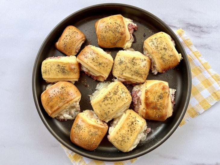 Uma assadeira com enroladinhos de presunto e queijo.