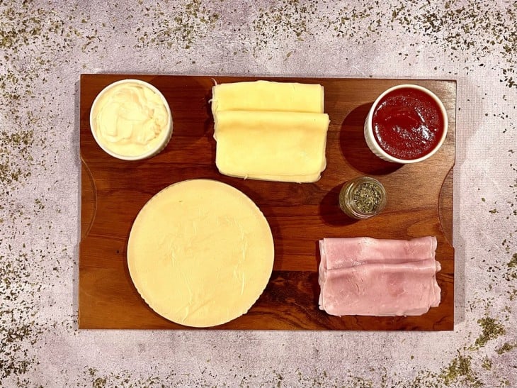 Ingredientes do enroladinho de presunto e queijo reunidos na bancada.