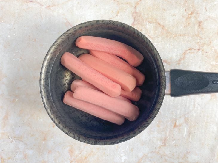 Salsichas em uma panela com água.