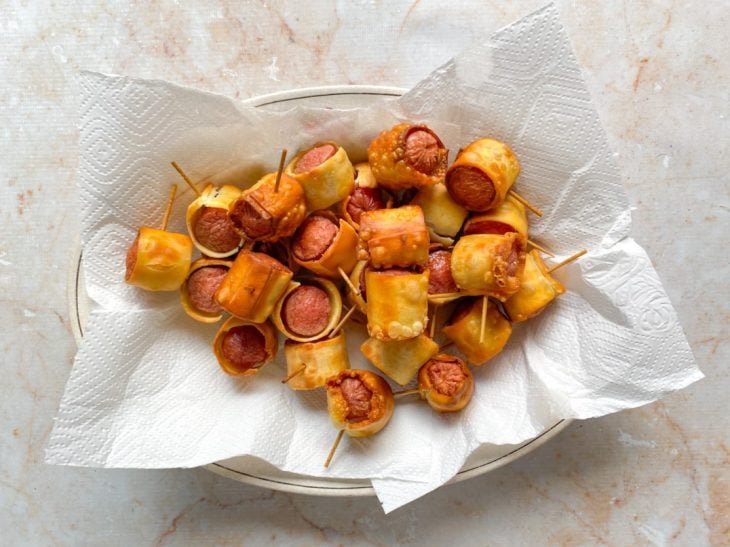 Enroladinhos de salsicha fritos em um recipiente forrado por papel toalha.