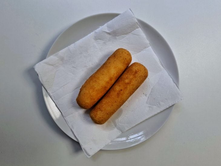 Enroladinhos fritos e acomodados em um prato forrado por papel toalha.