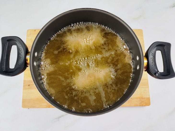 Enroladinhos de salsicha simples fritando em óleo quente.