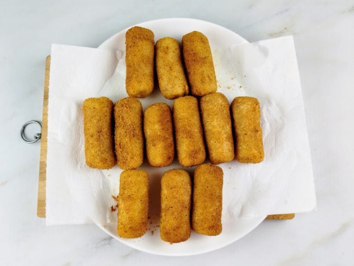 Enroladinhos de salsicha simples fritos e reservados em um prato com papel-toalha.