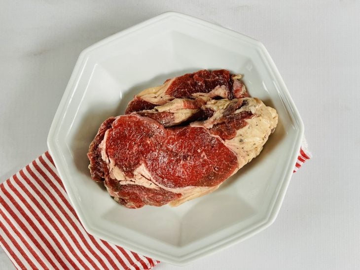 Um prato contendo dois bifes crus de entrecot.