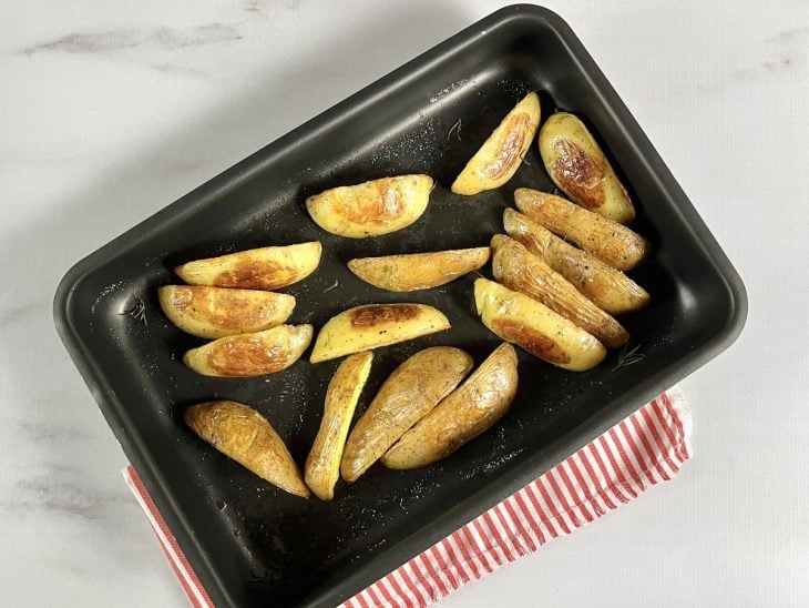 Uma forma contendo batatas cortadas e assadas.