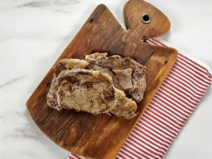Uma tábua contendo 2 bifes de entrecot assados.