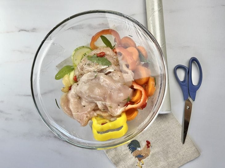 Um recipiente com a mistura para a marinada coberto por plástico filme.