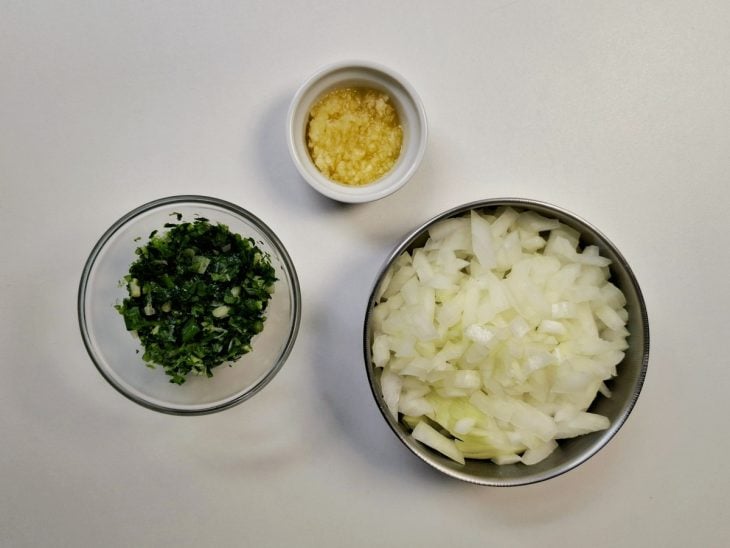 Alho, cebola, salsinha e cebolinha picados em potes pequenos.