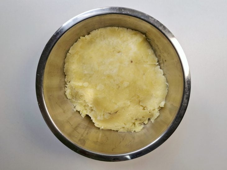 Batatas cozidas amassadas dentro de um recipiente de alumínio.