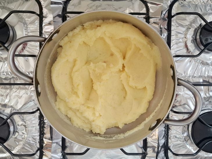 Batatas amassadas adicionadas a panela com leite e manteiga.