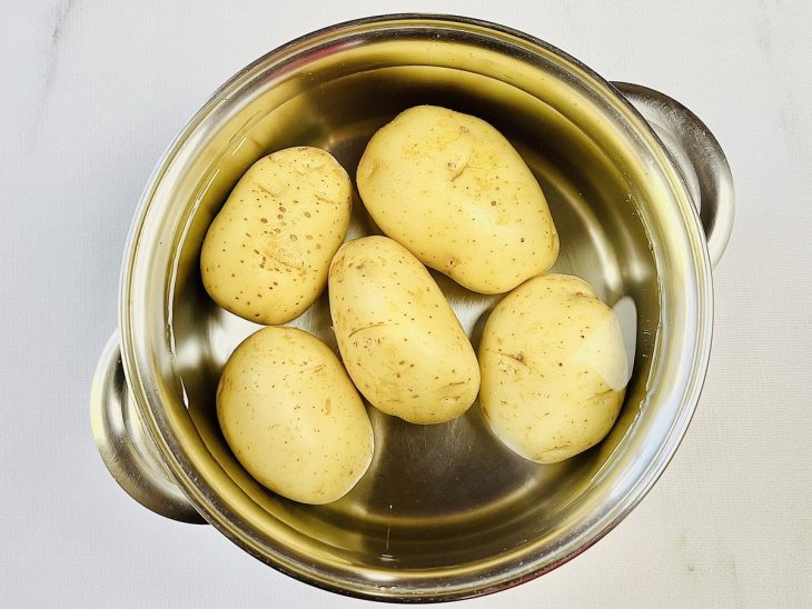 Batatas cozinhando na mesma panela com água.